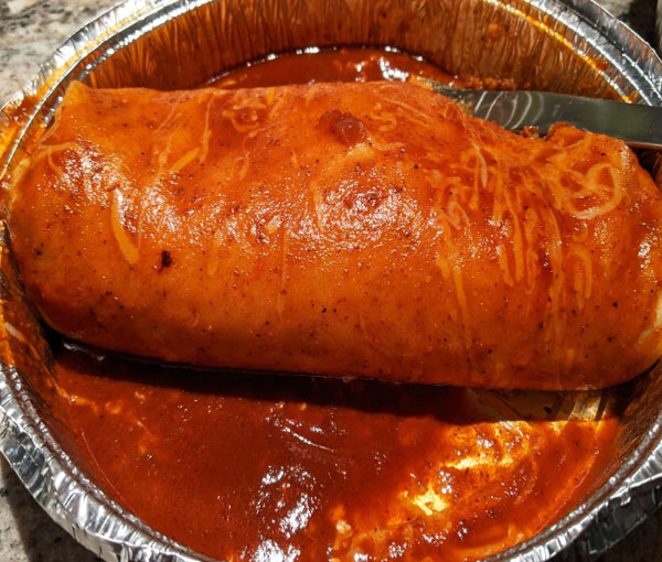 Large burrito covered in red enchilada sauce